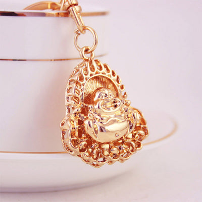 Close-up of a gold-tone Laughing Buddha pendant hanging from a clasp.