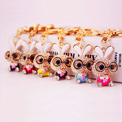 Six rabbit keychains in assorted body colors lined up on a pale background.