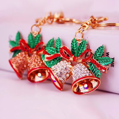 Two double bell keychains with clear and peach rhinestones on a pink background.