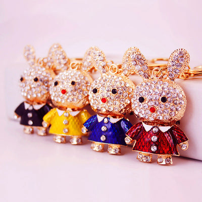 Four rhinestone rabbit keychains wearing black, yellow, blue, and red shirts.