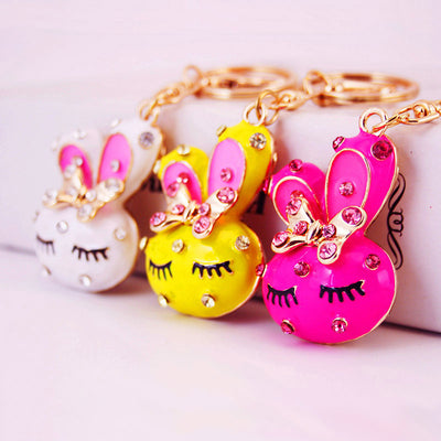 White, yellow, and rose red bunny keychains arranged together.