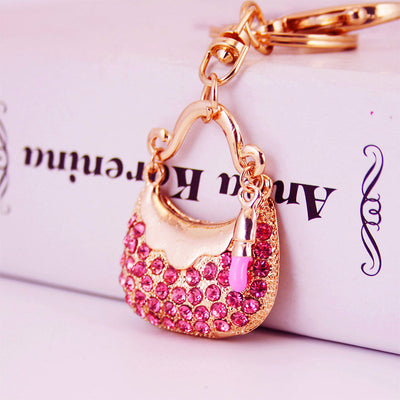 Close-up of a pink rhinestone handbag charm with a matching lipstick accent.