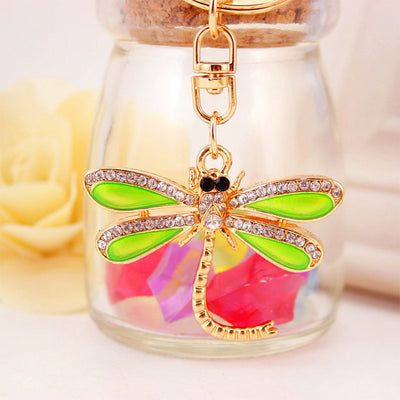 Front-facing green dragonfly keychain displayed against a glass jar.