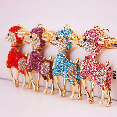 Four gold-tone goat charms covered with red, purple, blue, and pink rhinestones stand in a row.