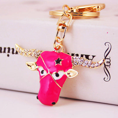 A fuchsia bull-head charm hangs from a gold-tone split ring and clasp.
