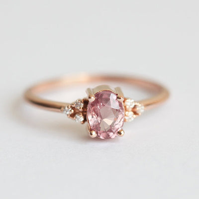 Product view showing rose-gold-tone pink oval three-stone ring