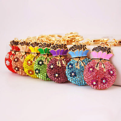 Seven crystal-covered money bag keychains displayed in red, peach, yellow, green, purple, blue, and pink.
