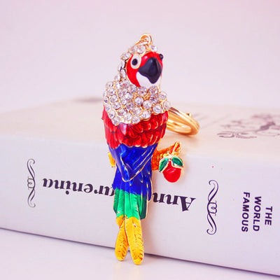 Angled front view of a colorful parrot beside a small red apple charm.