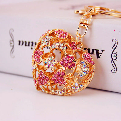 Close-up of a gold-tone openwork heart charm set with pink and iridescent stones.