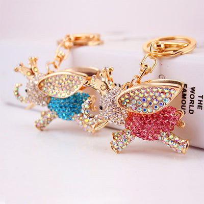 Pink and blue jeweled elephant keychains are shown together in a close-up.