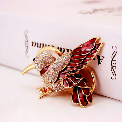 Close-up of a red and gold-tone bird charm covered with clear rhinestones