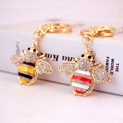 Two gold-tone bee keychains display yellow-black and red-white striped bodies.