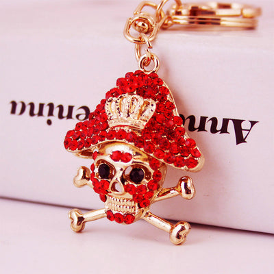 Close-up of a red rhinestone skull and crossbones charm with gold-tone key hardware.