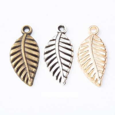 Grouped front views of the veined leaf metal charm in three metallic finishes
