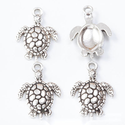 Turtle connectors with open filigree shells and lower loops arranged together on a white background.