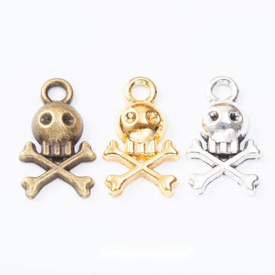 skull and crossbones metal charms in three finishes shown together in the available finishes