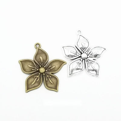 Grouped front views of the layered five petal flower charm in two antique finishes