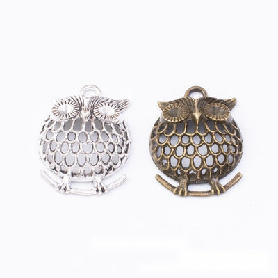 Product photo 1 of the openwork owl charm highlighting its round owl body with open feather cutouts and large eyes