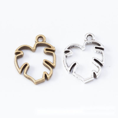 Front display of open monstera leaf bezel charm shown against a plain background.