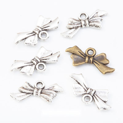 tied ribbon bow metal charms in two antique finishes shown together in the available finishes