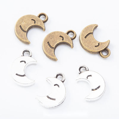 Crescent moon charms with cutout smiling faces arranged together on a white background.