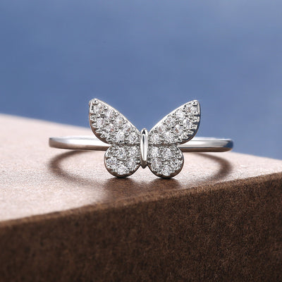 Silver pavé CZ butterfly thin band ring on brown block blue sky