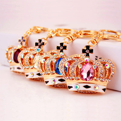 Four crown keychains with pink, blue, white, and red center stones are arranged in a row.