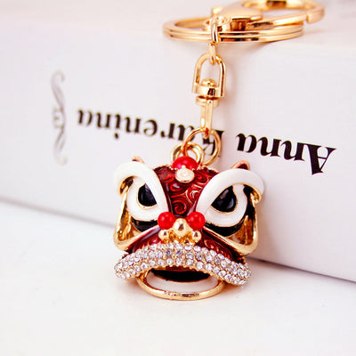 Close-up of the red lion dance head charm attached to a gold-tone split ring.