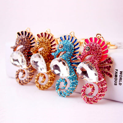 Four stone-covered seahorse keychains displayed together in gray, coffee brown, blue, and pink.