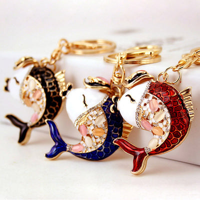 Three fish keychains in black, blue, and red arranged on a white background.