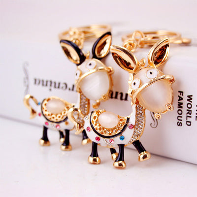Two gold-tone donkey keychains with different ear colors stand side by side.