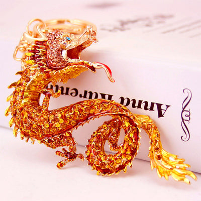 Close-up of a gold-tone coiled dragon keychain resting against a book.