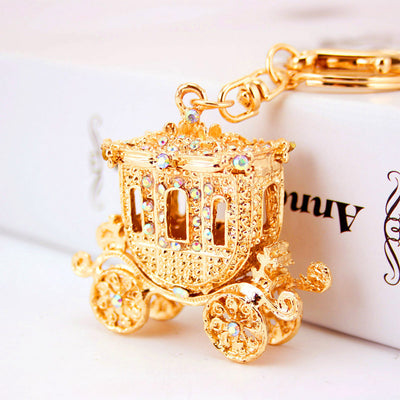 Angled close-up of an ornate gold tone carriage charm set with iridescent rhinestones.