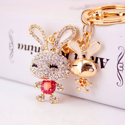 Close-up of a pink-accented rhinestone rabbit beside a small gold tone rabbit charm.