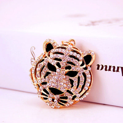 A rhinestone tiger face charm shown upright beside a white box.