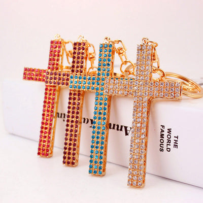 Four gold-tone cross keychains covered with pink, purple, blue, and clear rhinestones.