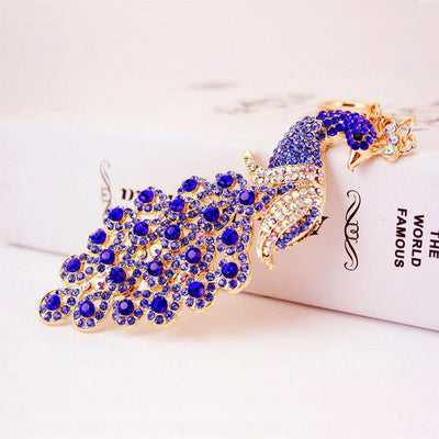 Deep blue rhinestone peacock ornament rests diagonally on a white book.