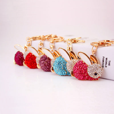 Five rhinestone rabbit keychains arranged in magenta, red, purple, blue, and pink.