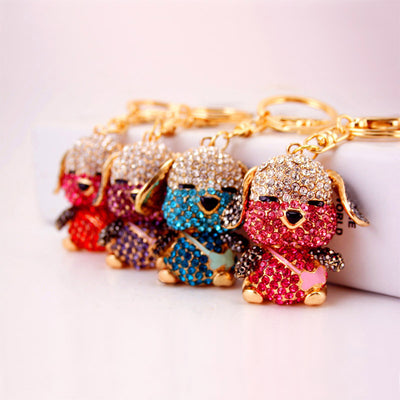 Four clear-and-colored rhinestone dog keychains arranged in a row.