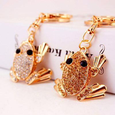 Two gold-tone frog keychains display clear and brown faceted accents side by side.