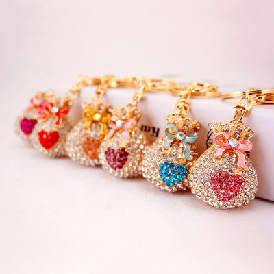 Six jeweled money bag keychains arranged in a row with different colored hearts and bows.