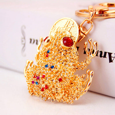 Close view of a gold-tone toad keychain covered with multicolor faceted stones.