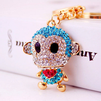 Close-up of a blue rhinestone monkey charm with a red heart accent and gold-tone key ring.