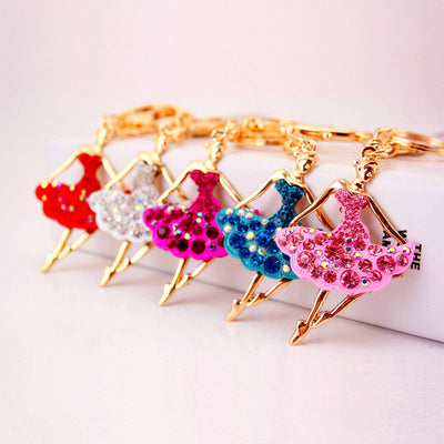 Five ballerina keychains in red, white, magenta, blue, and pink arranged in a row.