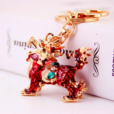 Close-up of a red qilin keychain with gold-tone details and green and clear faceted accents.