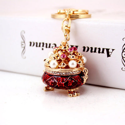 Close view of a red bowl-shaped keychain decorated with pink stones and pearl-like beads.