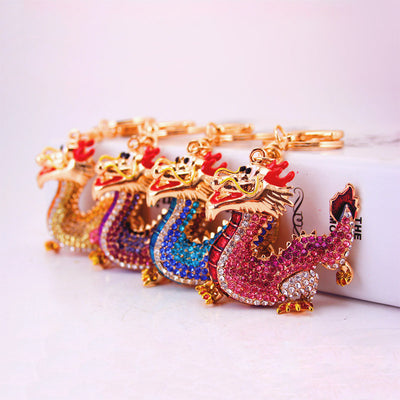 Four dragon keychains in pink, blue, purple, and gold tones displayed in a row.
