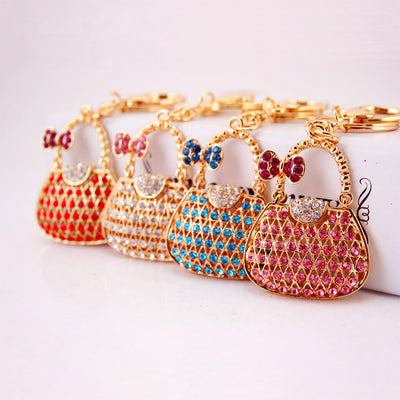 Four gold-tone handbag keychains with red, clear, blue, and pink rhinestones.