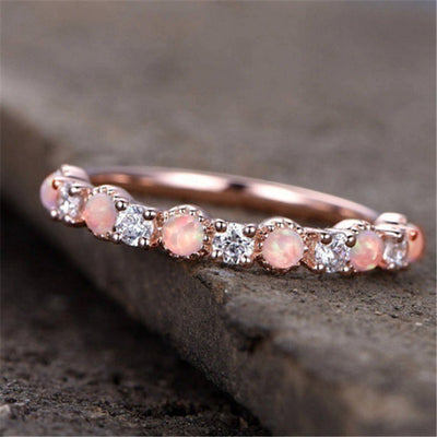 Rose gold opal and clear eternity stacking ring on dark stone