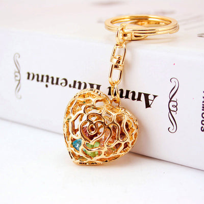 Front view of a gold-tone openwork heart keychain containing colorful faceted pieces.